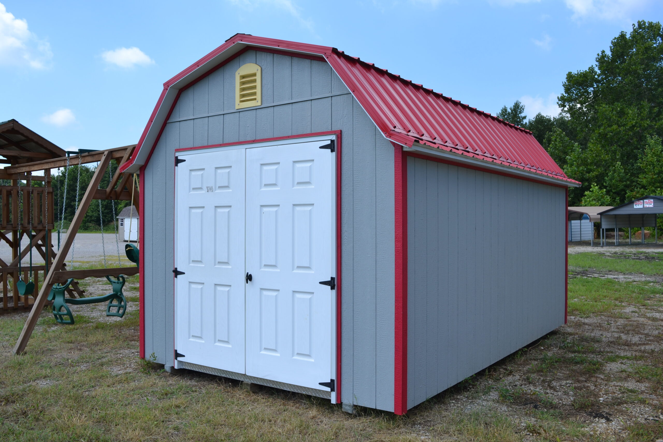 10x16 Lofted Gambrel Barn shed with gray siding, red trim, white double doors, a yellow gable vent, and red metal roofing.