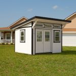 Classic Studio Shed with white siding, black trim, double doors with windows, a slanted roof, and transom windows.