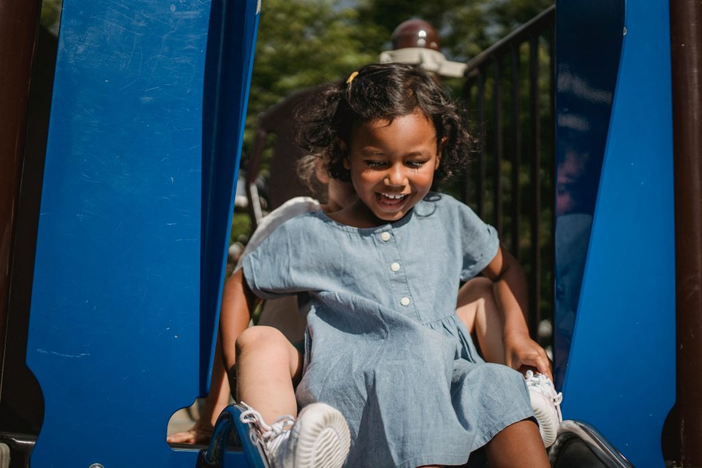 Two children doing down a slide together.