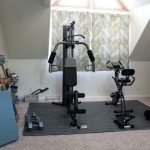 Home gym set up with a weight system, dumbbells, and a stationary bike.